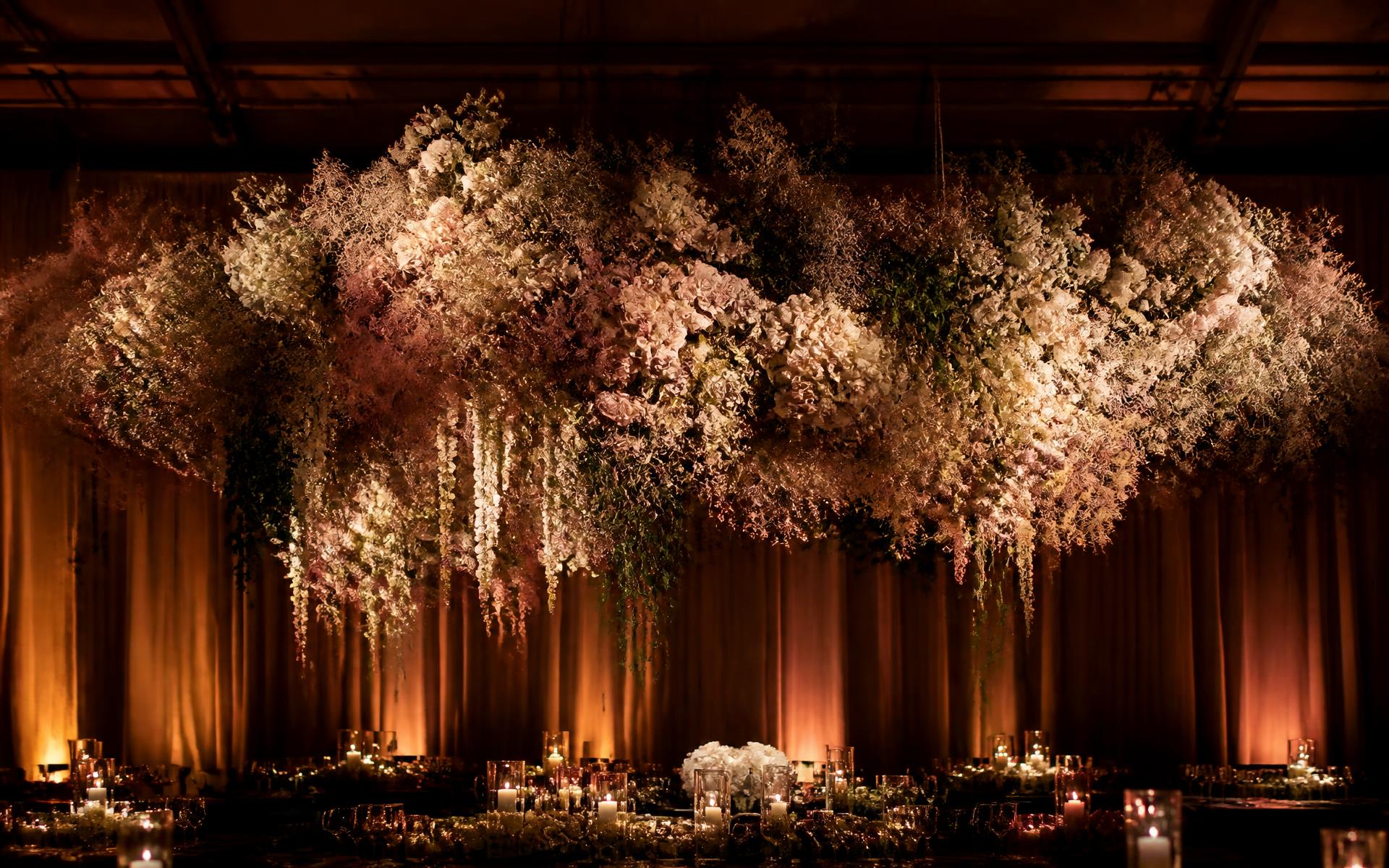 Suspended floral installation above a dimly lit event space